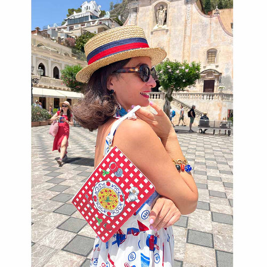 Model in dress shows red gingham Italian design purse