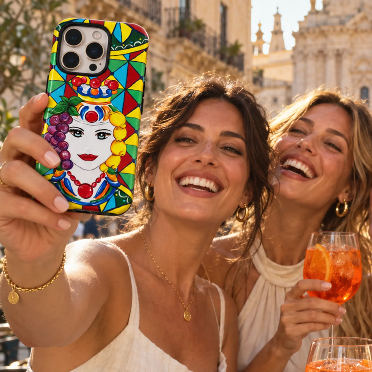 Women hold Testa Di Moro phone case with bright Sicilian design with cocktail Spritz