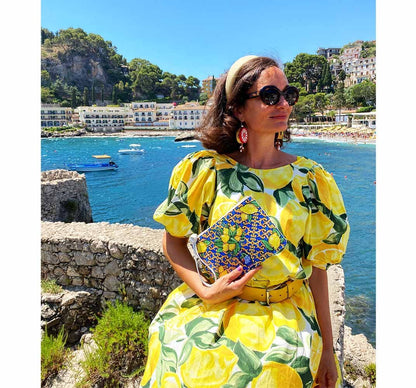 Model in yellow lemon dress wears lemon purse in Taormina