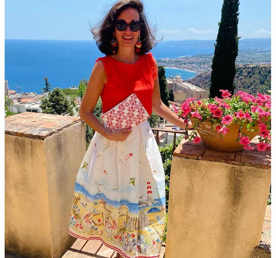 Stunning model in dress shows red maiolica tile clutch bag purse in Taormina Sicily